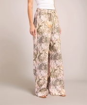 Person wearing camouflage-patterned wide-leg pants on a plain background