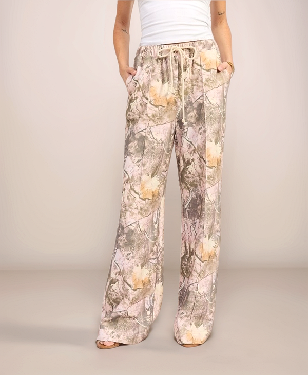 Woman wearing camouflage-patterned pants on a plain background