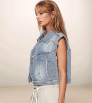 Woman wearing a light blue denim vest against a plain background