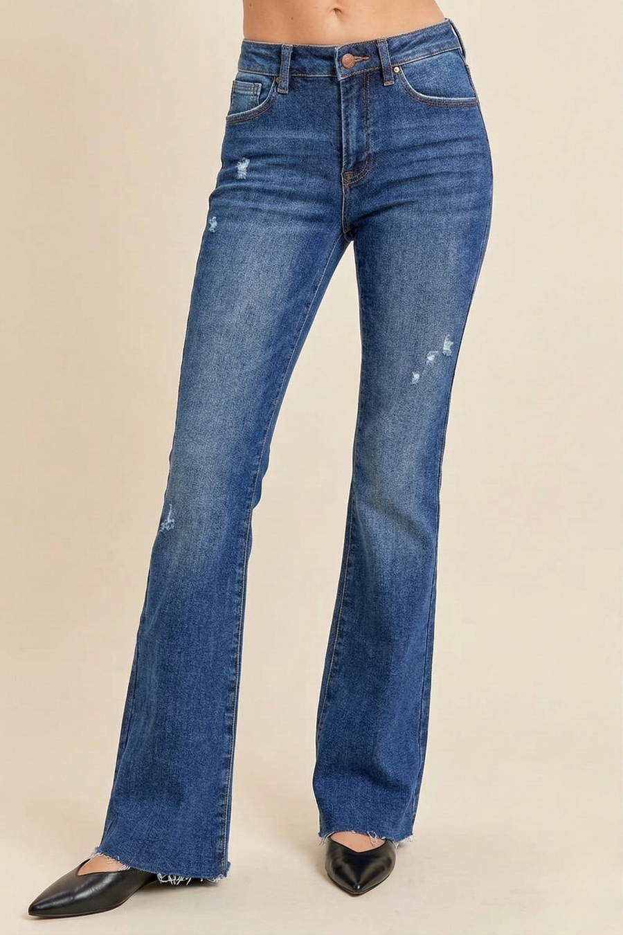 a woman wearing lightly distressed vintage flare jeans on a neutral background