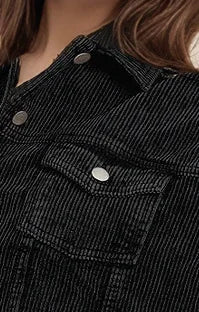 Close-up of a black corduroy jacket with buttons and a pocket.