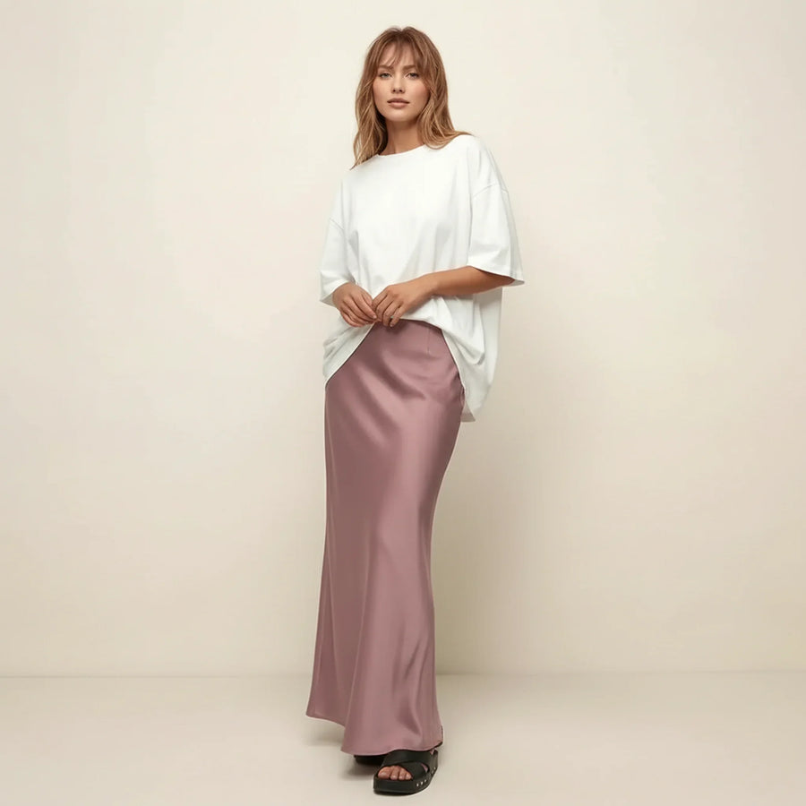 Woman wearing a white top and pink skirt against a beige background