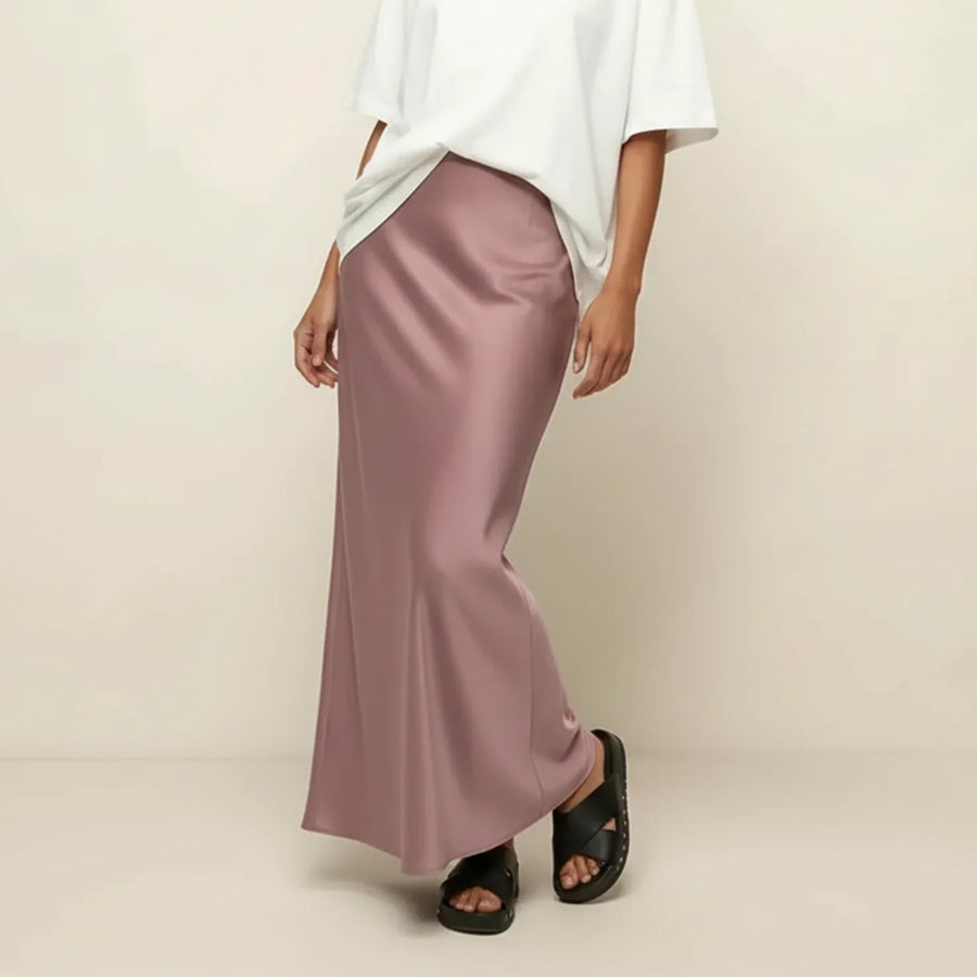 Woman wearing a white top and pink satin skirt on a beige background