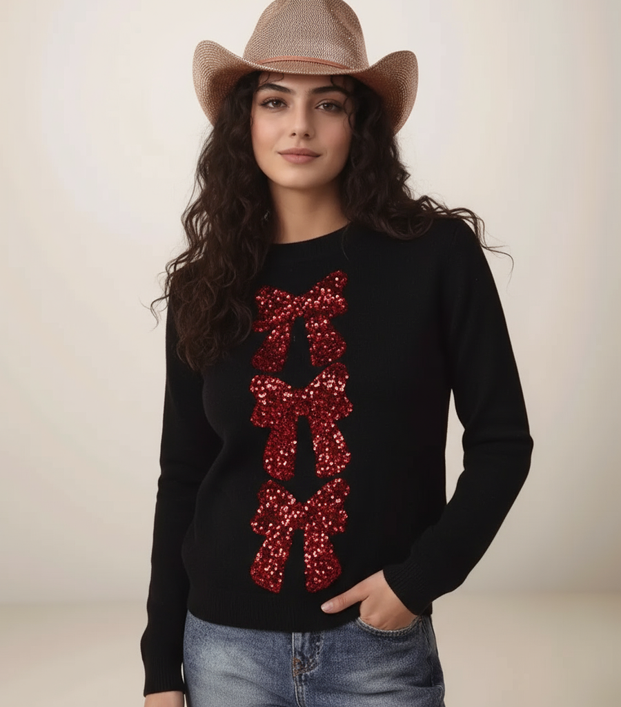 Woman wearing a black sweater with red sequin bows and a cowboy hat on a plain background