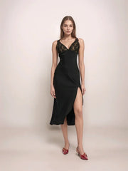 a woman wearing a black slip dress with a side slit and lace contrast on the bodice.