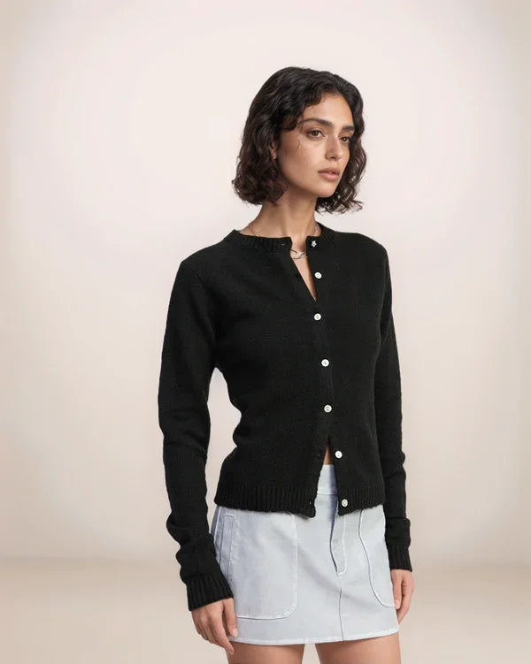 Woman wearing a black cardigan over a light blue top on a beige background