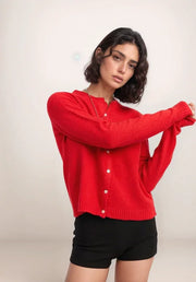 Woman wearing a red cardigan and black shorts on a white background