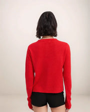 Person wearing a red sweater and black shorts on a plain background