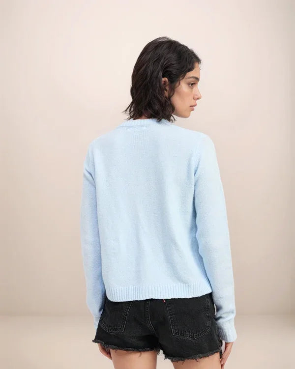 Person wearing a light blue sweater and black shorts on a beige background