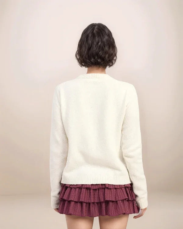 Person wearing a white sweater and maroon skirt on a plain background
