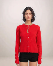 Woman wearing a red cardigan over a black top against a plain background