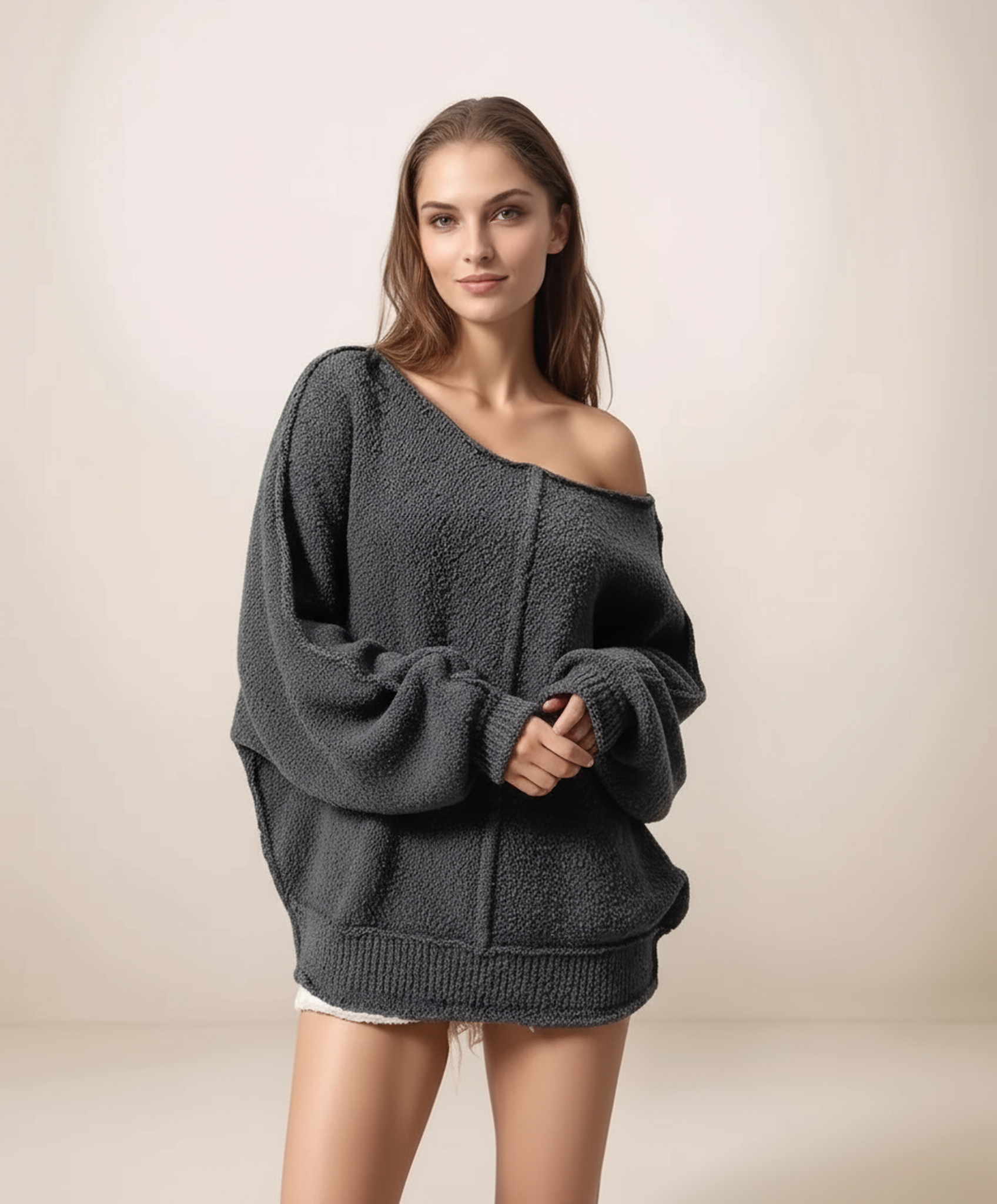 Woman wearing a dark gray off-shoulder sweater on a plain background