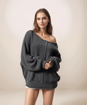 Woman wearing a dark gray off-shoulder sweater on a plain background