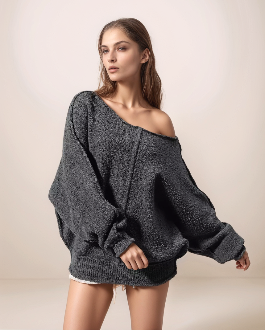 Woman wearing a dark gray off-shoulder sweater against a plain background