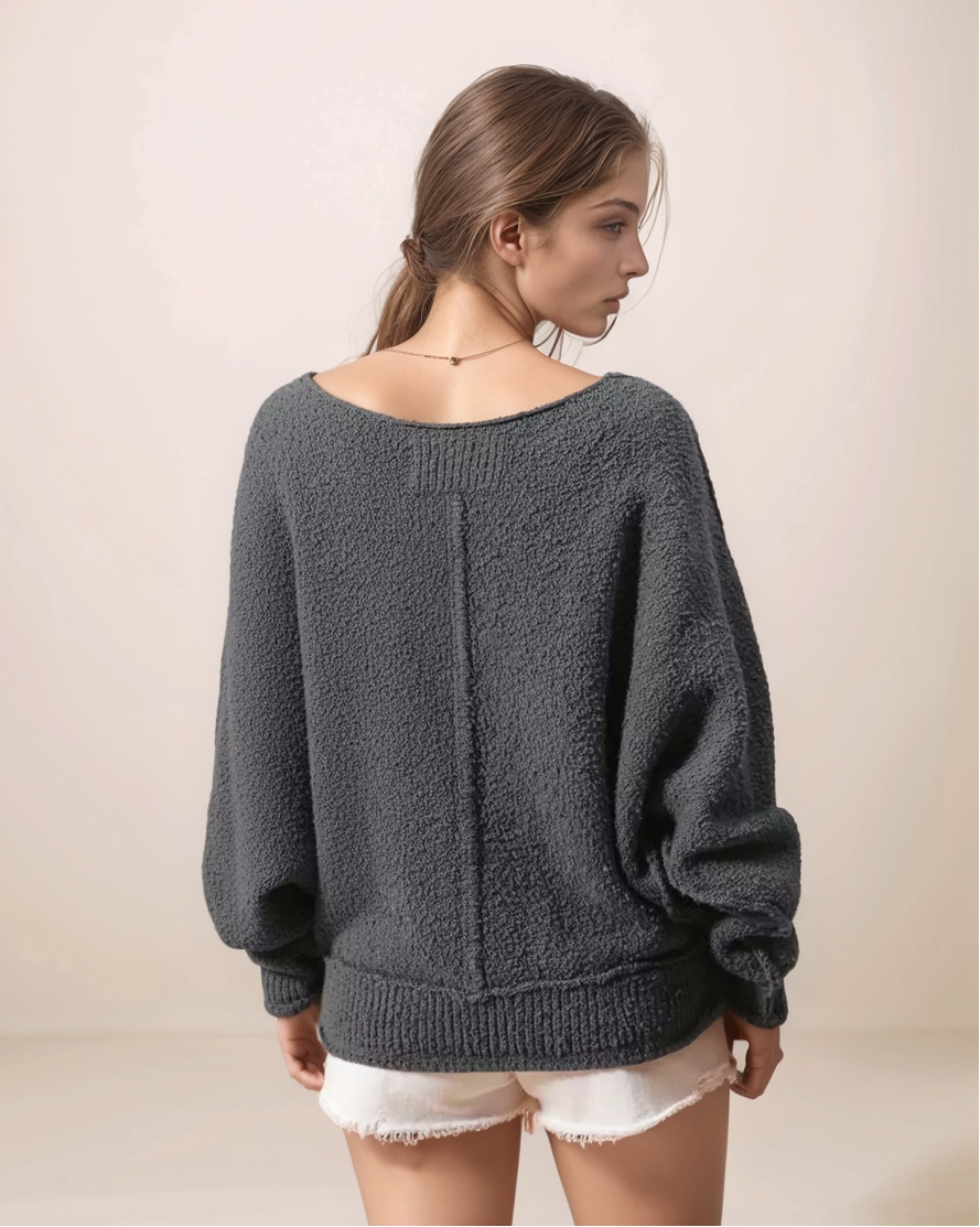 Woman wearing a dark gray sweater against a beige background