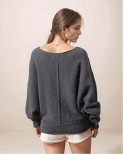 Woman wearing a dark gray sweater against a beige background