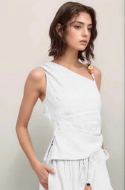 an angled view of the white Sonora Asymmetrical Top, featuring a sophisticated one-shoulder neckline and flattering ruched pleating along the side.
