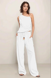 Full-body shot of a model wearing the complete Sonora set in white, featuring the asymmetrical embellished top and matching wide-leg pant.