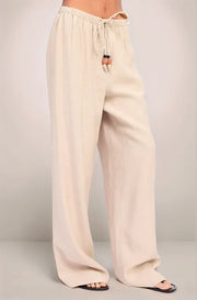 An angled view of the sand-colored Sonora pants, focusing on the high-quality Rayon-Linen texture and the artisanal drawstring tie with stone and bead embellishments.