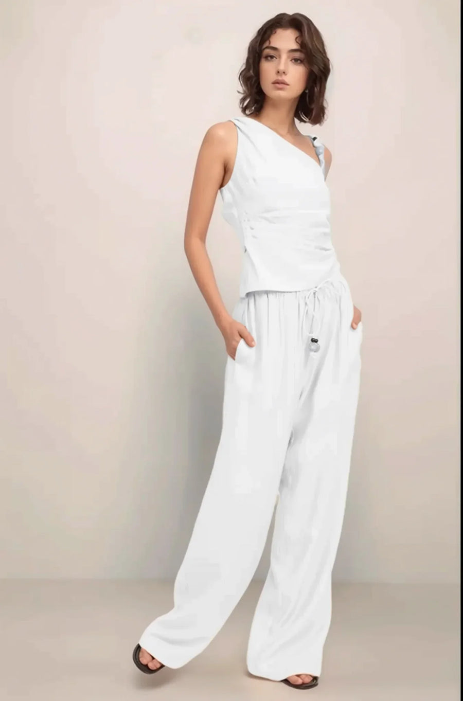 Front view of a model wearing the complete Sonora set in white, featuring the asymmetrical one-shoulder top and baggy wide-leg pants.