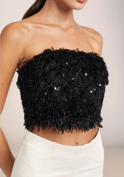 Black strapless textured top with sequins worn by a person on a plain background