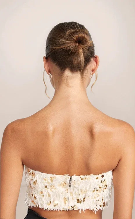 Back view of a woman wearing a strapless white lace top against a plain background