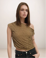 Woman wearing a sparkly gold top against a plain background