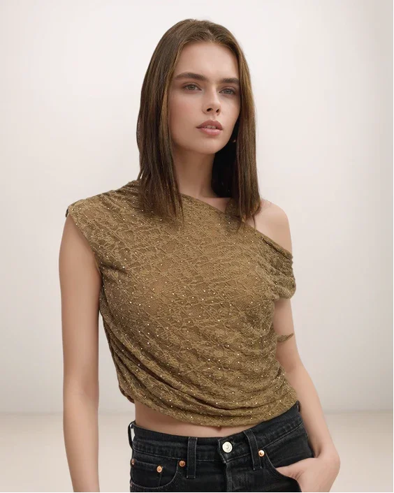 Woman wearing a sparkly gold top against a plain background