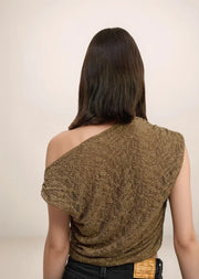 Woman wearing a patterned brown top against a plain background