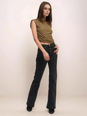 Woman wearing a green sleeveless top and black jeans against a white background