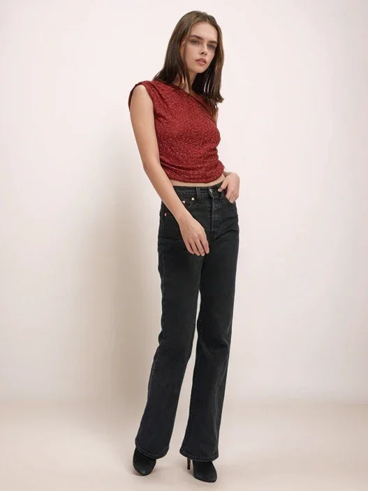Woman wearing a red top and black jeans against a white background