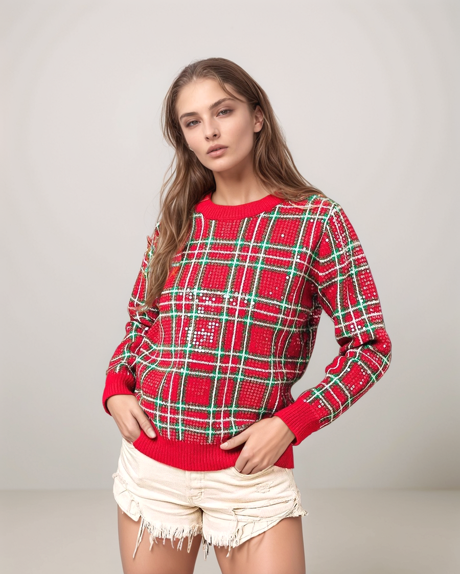 Woman wearing a red and green plaid sweater with white shorts on a gray background