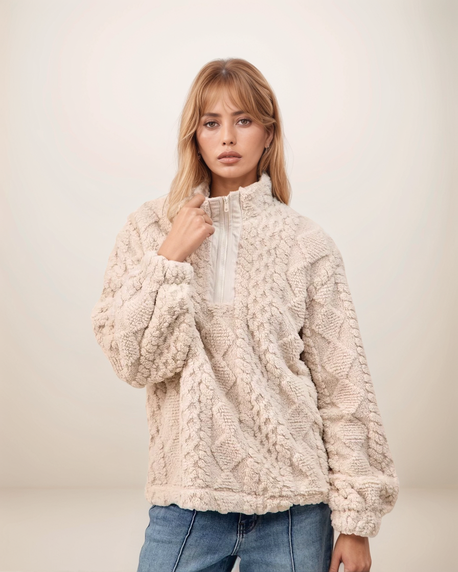 Woman wearing a cream knitted sweater against a plain background