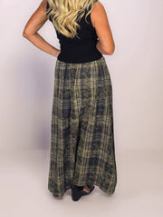 Person wearing a black top and plaid skirt on a plain background