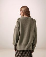 Person wearing a gray sweater with a neutral background