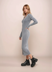 Woman wearing a ribbed knit dress with black boots on a beige background