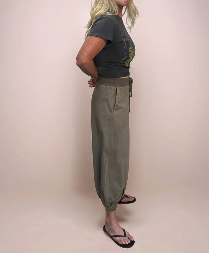 Blonde stylish woman facing sideways wearing a graphic t-shirt and stylish, comfortable cropped sweatpants.