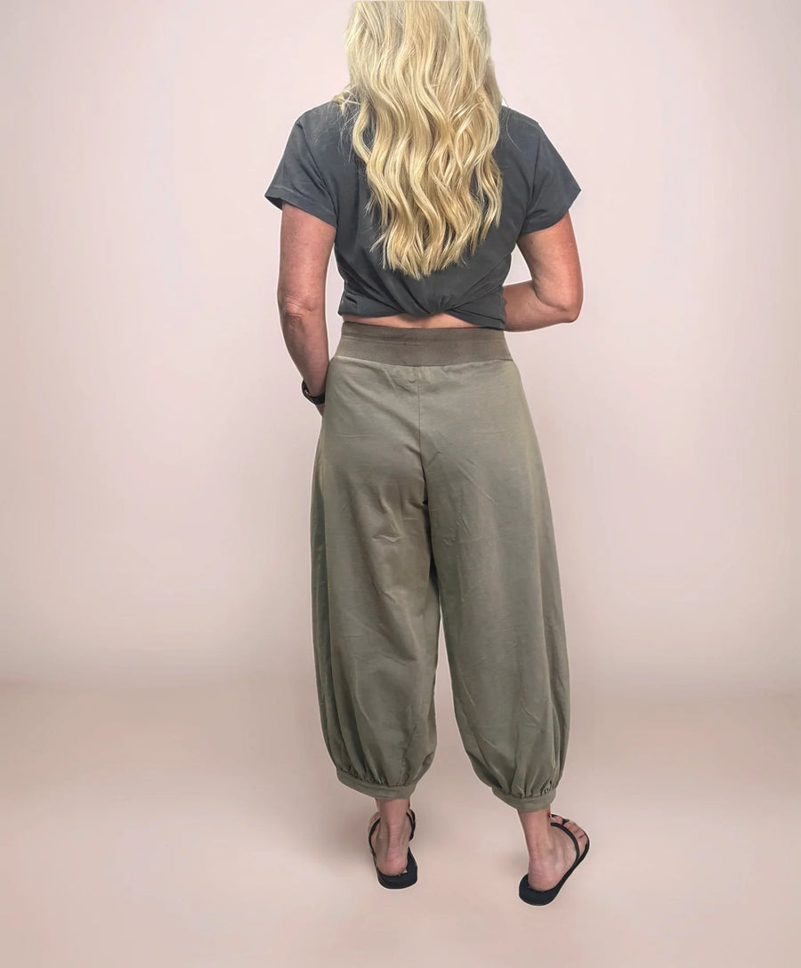 a blonde woman facing backwards wearing stylish cropped sweatpants with a cropped t-shirt and sandals