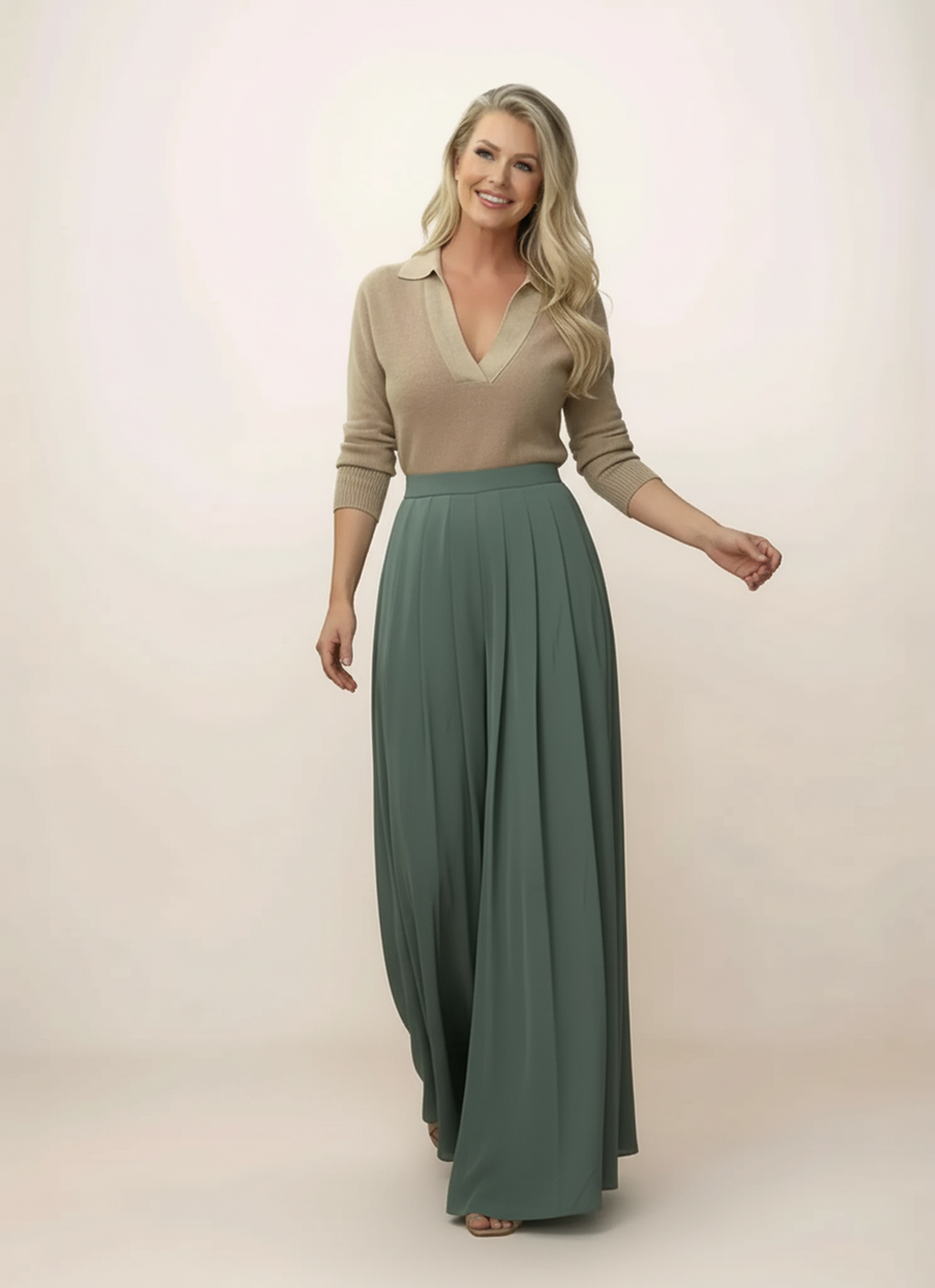 Woman wearing a beige top and green skirt on a plain background