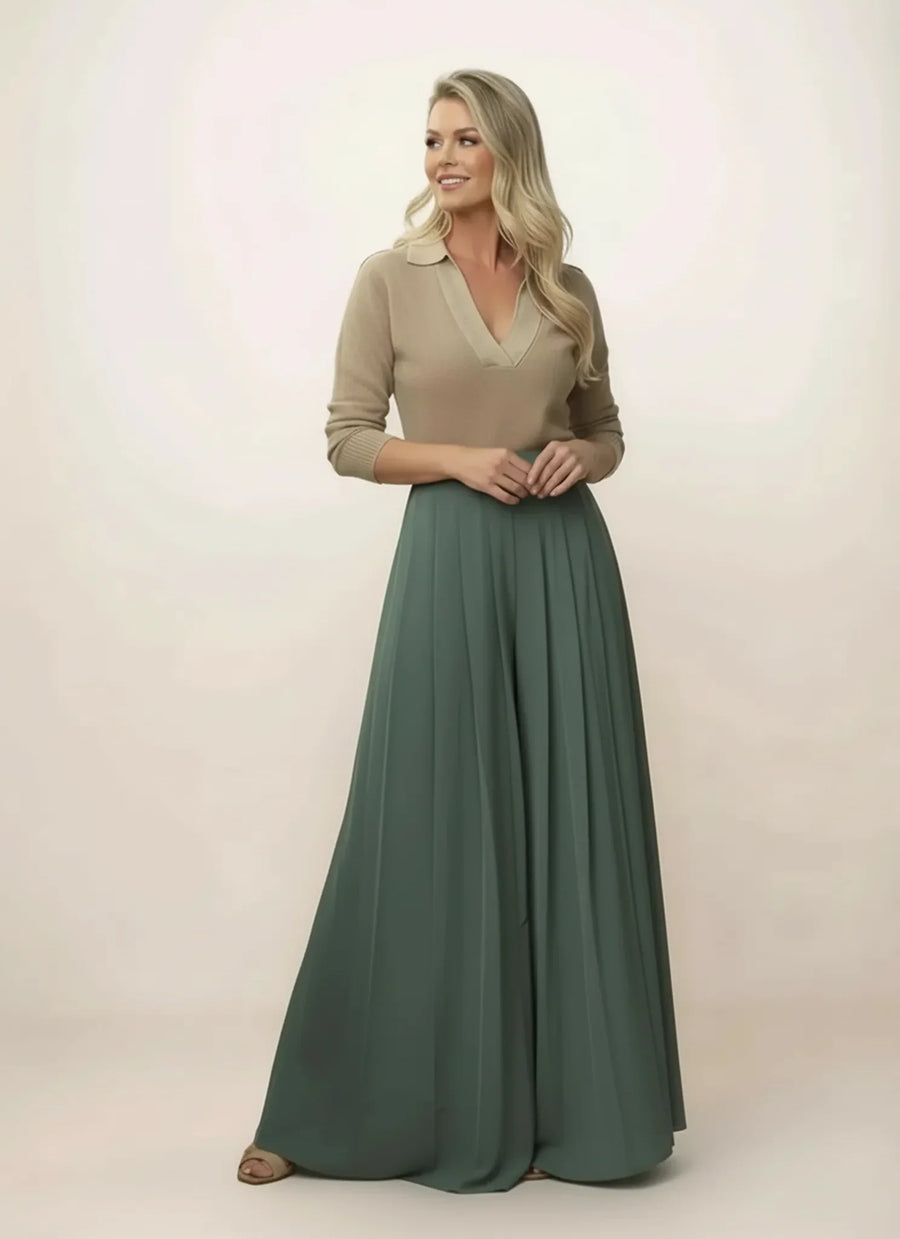 Woman wearing a beige top and green long skirt on a plain background