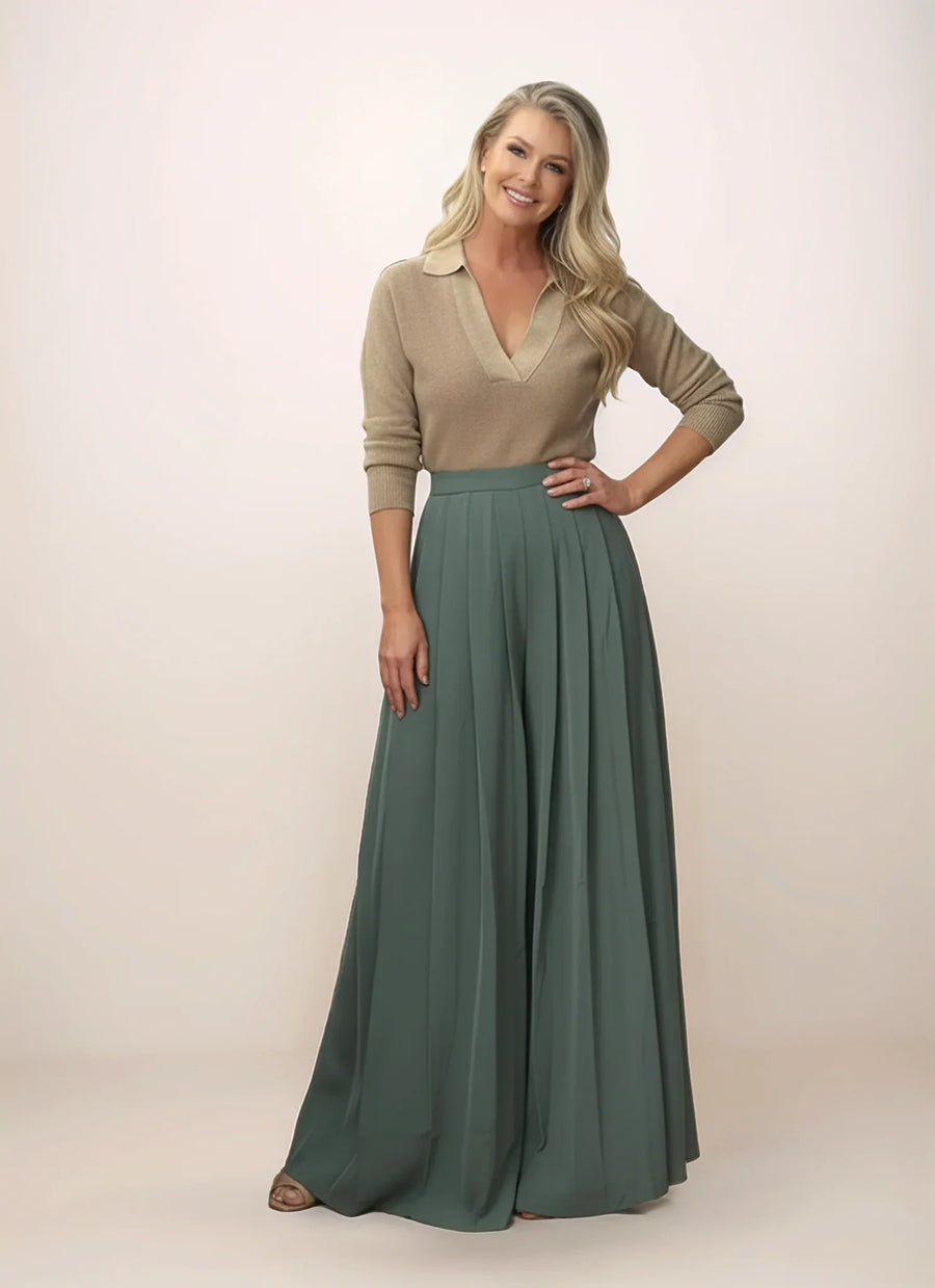 Woman wearing a beige top and green wide-leg pants on a plain background