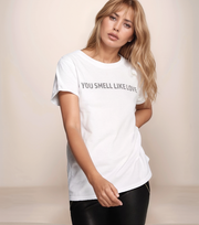 Woman wearing a white t-shirt with text, standing against a plain background